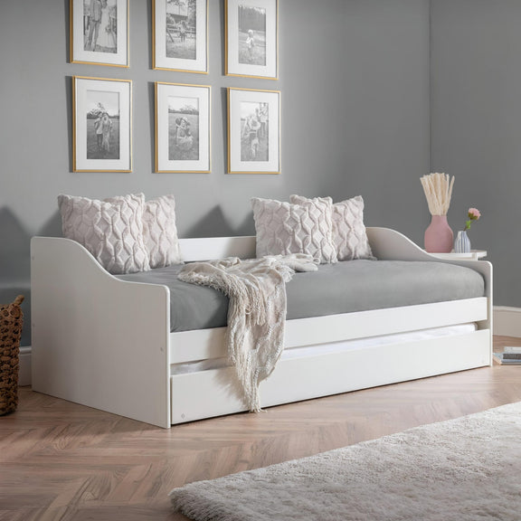 White daybed with gray bedding in a room with gray walls and framed pictures.