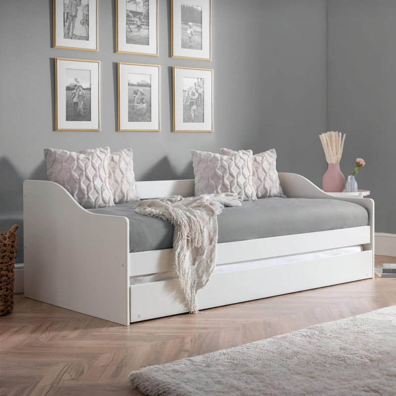 White daybed with gray bedding in a room with gray walls and framed pictures.