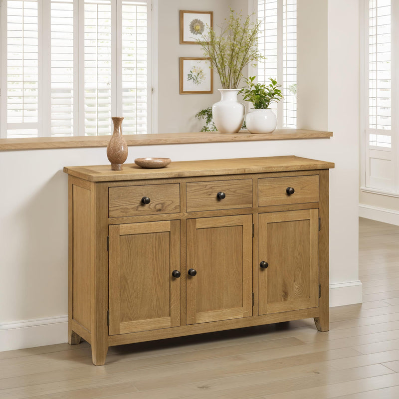 Wooden sideboard with decorative items in a room with light wood flooring and white walls.