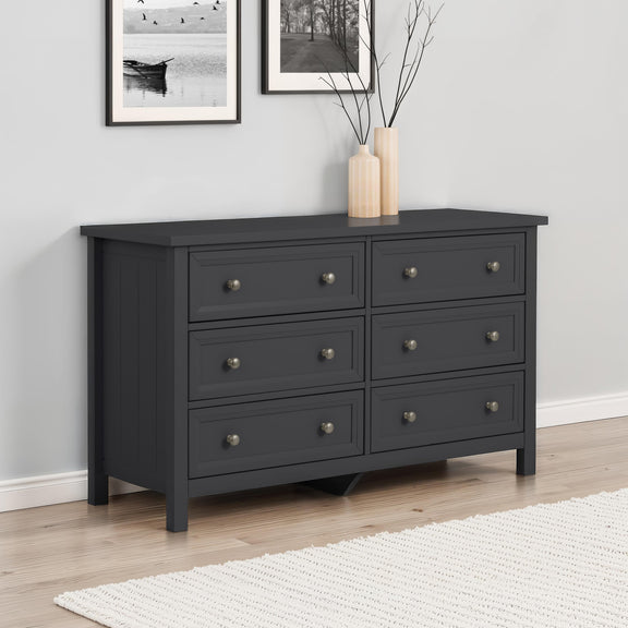 Black dresser with six drawers in a room with light gray walls and a white rug.
