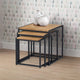 Set of three nesting tables with a white pitcher on top against a patterned wall.