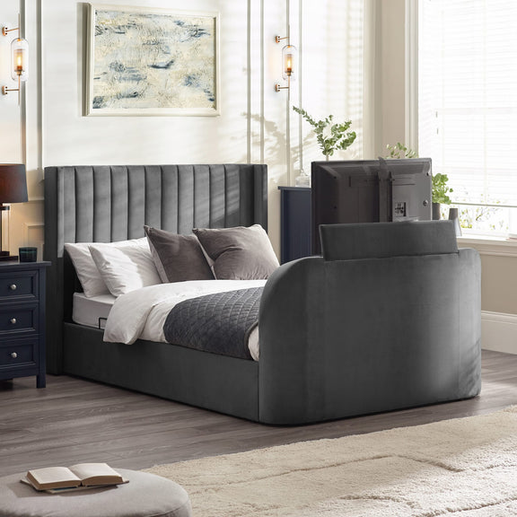 Gray upholstered bed in a bedroom setting with nightstands and decor.