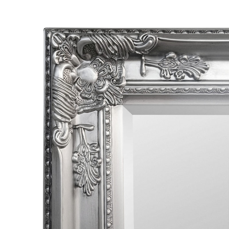 Decorative silver mirror frame with intricate designs on a white background