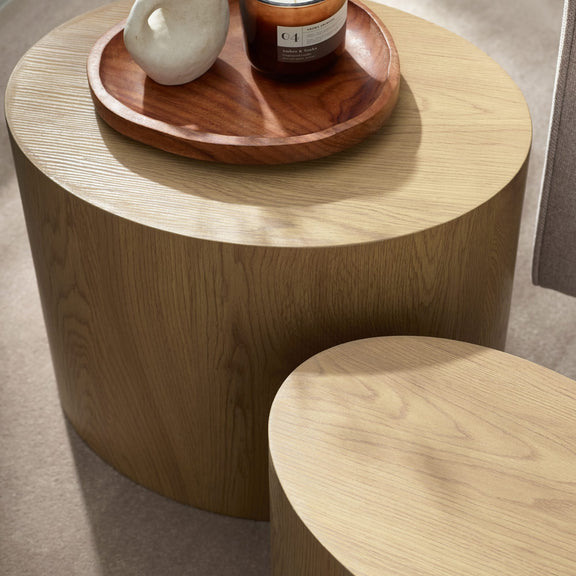 Wooden side table with a wooden tray holding decorative items on a neutral background
