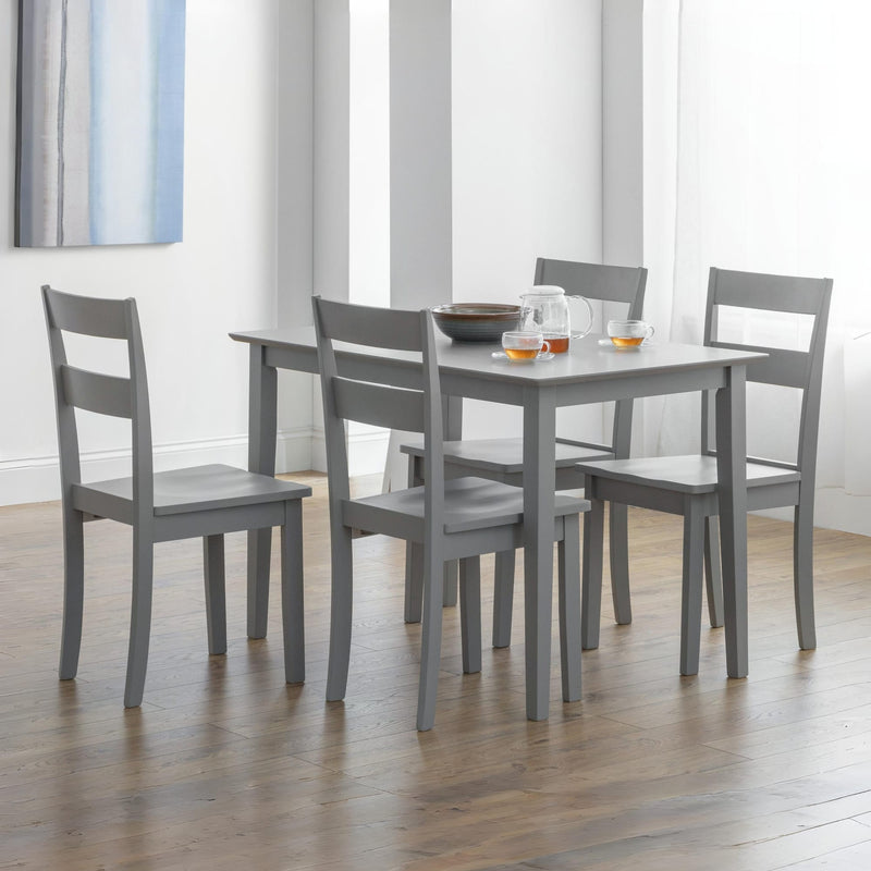 Gray dining table with four matching chairs in a room with light-colored walls and wooden flooring.