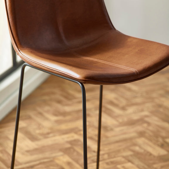 Brown leather chair with metal legs on a wooden floor
