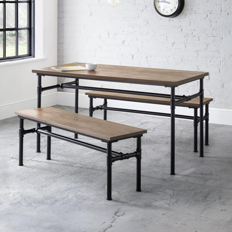 Dining table with benches in a room with white brick walls and a window.