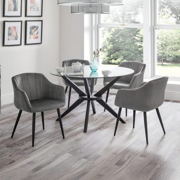 Dining room with a round glass table and gray chairs in front of large windows.