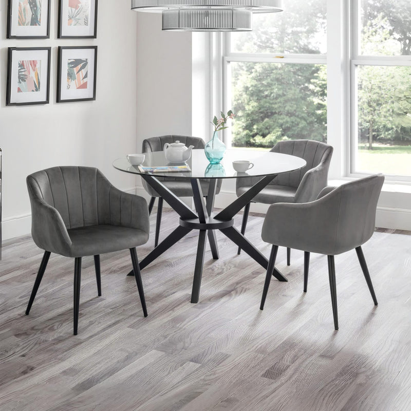 Dining room with a round glass table and gray chairs in front of large windows.