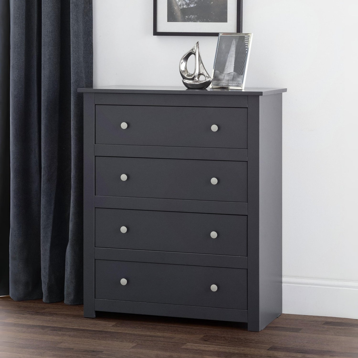 Dark gray dresser with four drawers in a room setting.