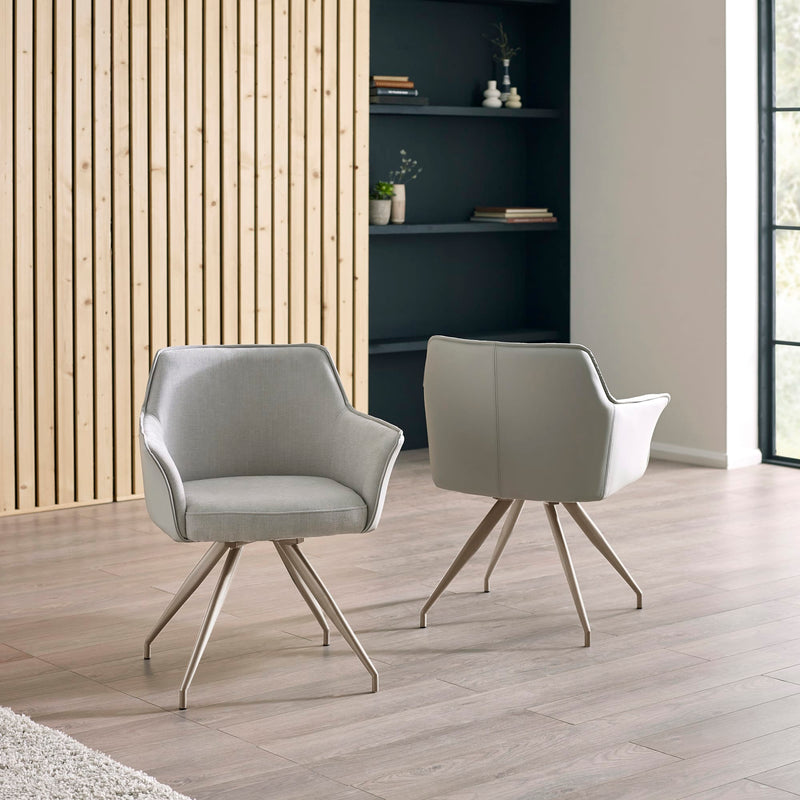 Two gray chairs with metal legs in a modern room with wooden flooring and a bookshelf.