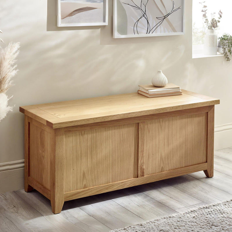 Wooden storage bench in a room with framed artwork on the wall.