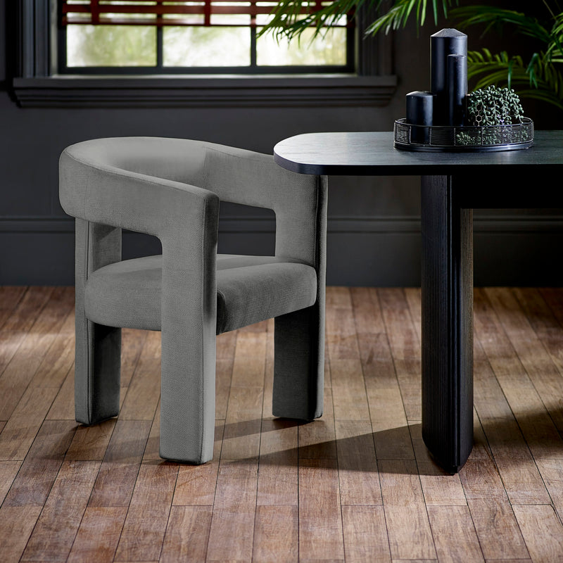 Modern gray chair and black table in a room with wooden flooring and a window.