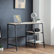 Modern desk with laptop, camera, and decorative items against a gray wall.