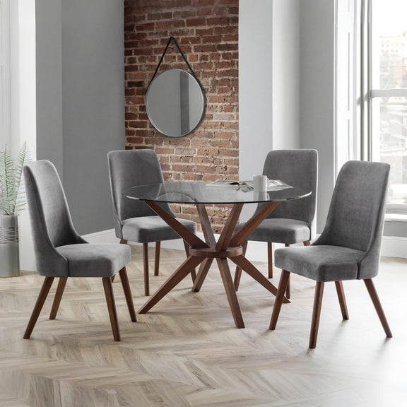 Dining room with a glass table and gray chairs against a brick wall.