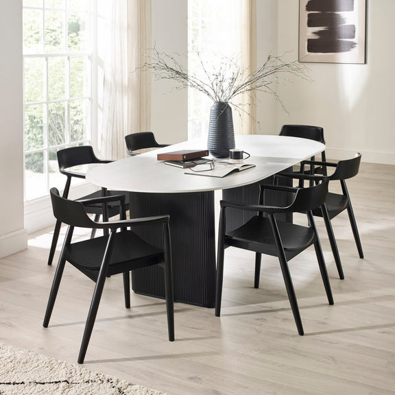 Modern dining room with a white oval table and black chairs.