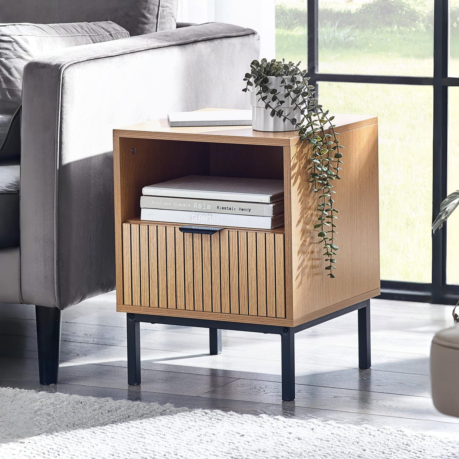 Wooden side table with books and a plant in a living room setting