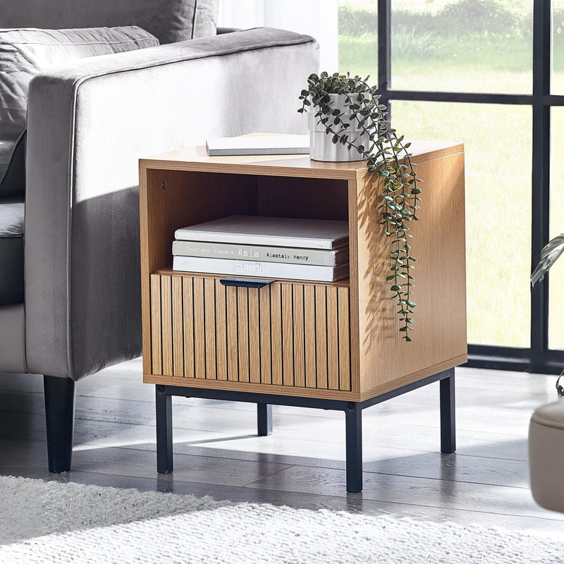 Wooden side table with books and a plant in a living room setting