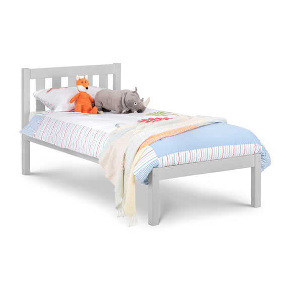 White children's bed with colorful bedding and stuffed animals on a white background