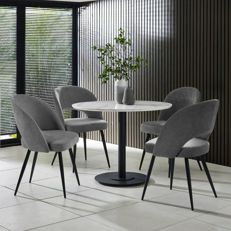 Dining table with four gray chairs in a modern interior setting.