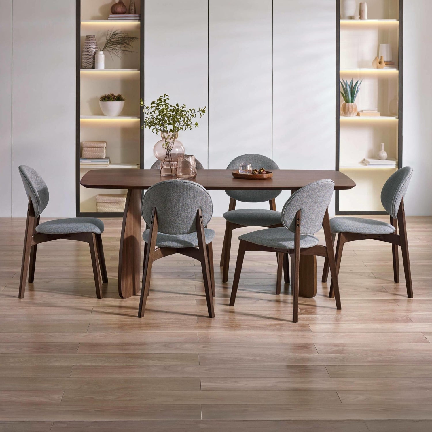 Dining room with wooden table and gray chairs in a modern interior setting.