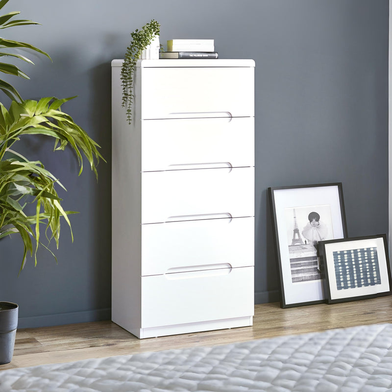 White dresser with decorative items against a gray wall with framed pictures.