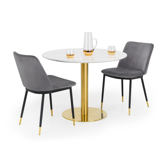 Round dining table with gold base and two gray chairs on a white background