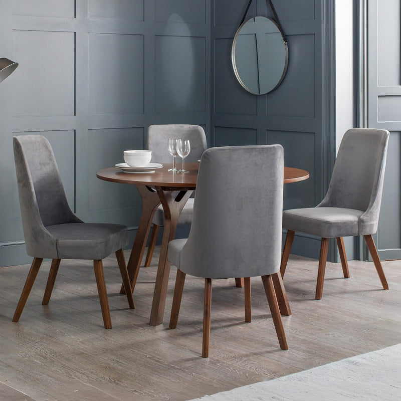 Dining room with a round wooden table and four gray chairs against a blue paneled wall.