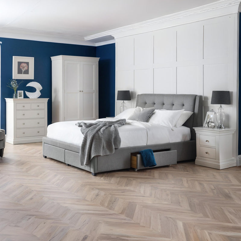 Modern bedroom with gray upholstered bed, white wardrobe, and nightstands.