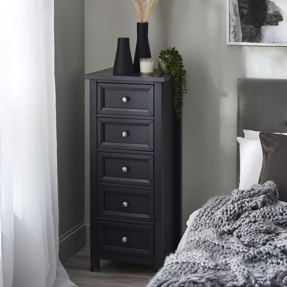 Black tall dresser with decorative items in a bedroom setting