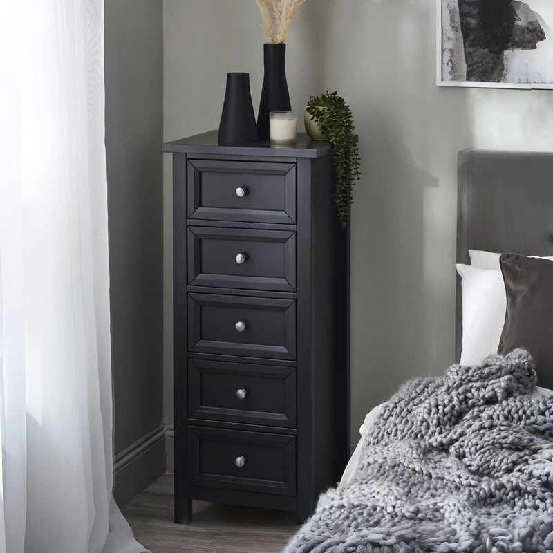 Black tall dresser with decorative items in a bedroom setting