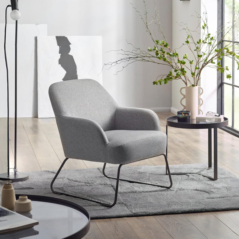 Gray armchair in a modern living room with a side table and decorative elements.
