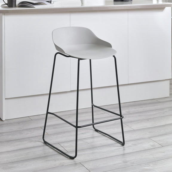 White bar stool with black legs on a light wooden floor in a kitchen setting.