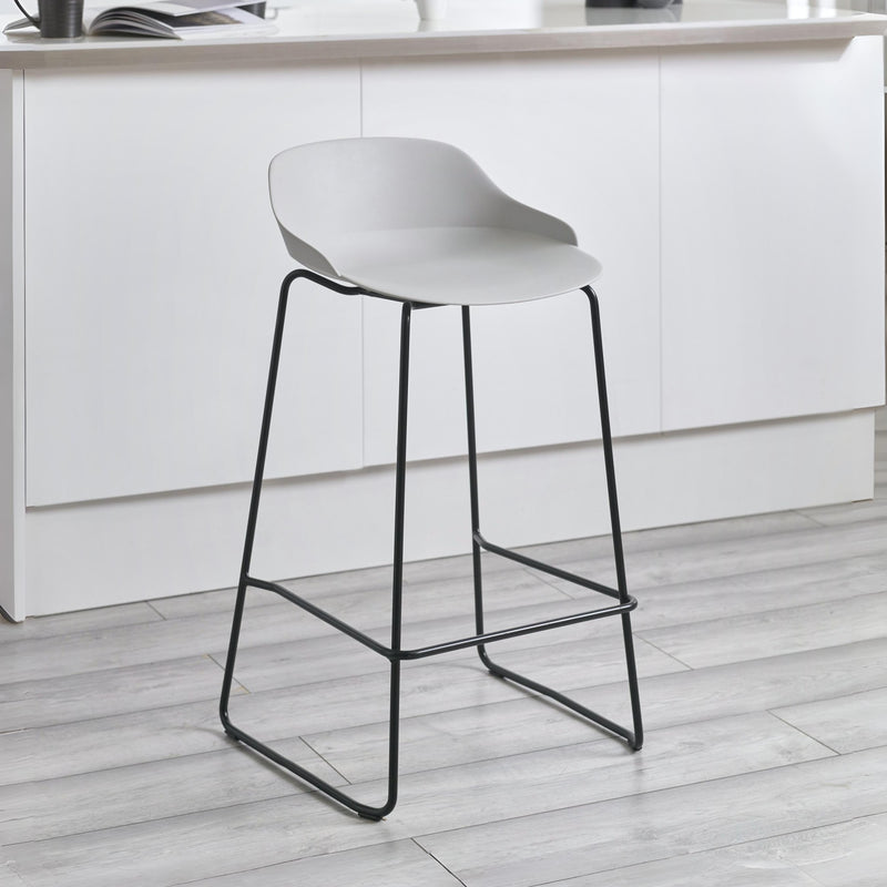 White bar stool with black legs on a light wooden floor in a kitchen setting.