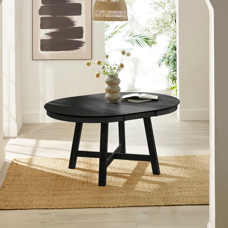 Black round coffee table with a vase and book in a bright room.