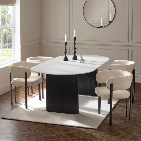 Modern dining room with a black and white oval table and chairs.