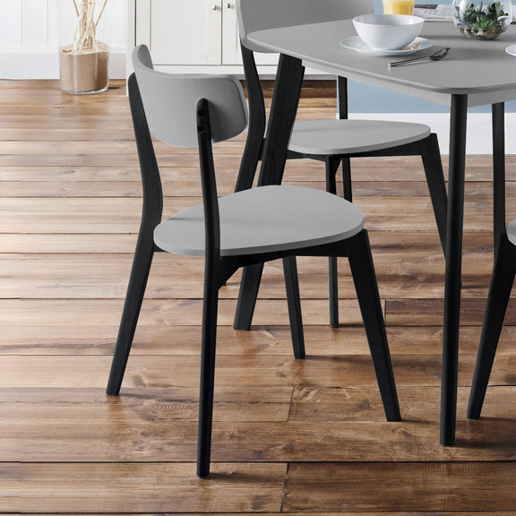 Dining chairs with gray seats and black legs on a wooden floor.