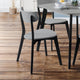 Dining chairs with gray seats and black legs on a wooden floor.
