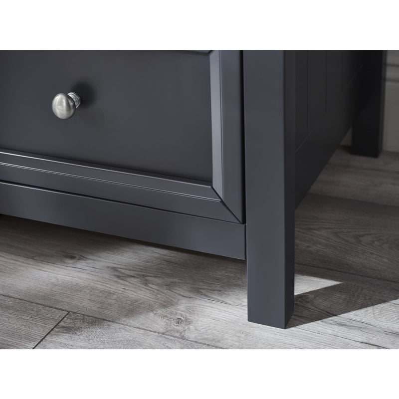 Dark gray wooden drawer with a knob on a wooden floor.