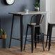 High table with bar stools against a gray wall with a clock.