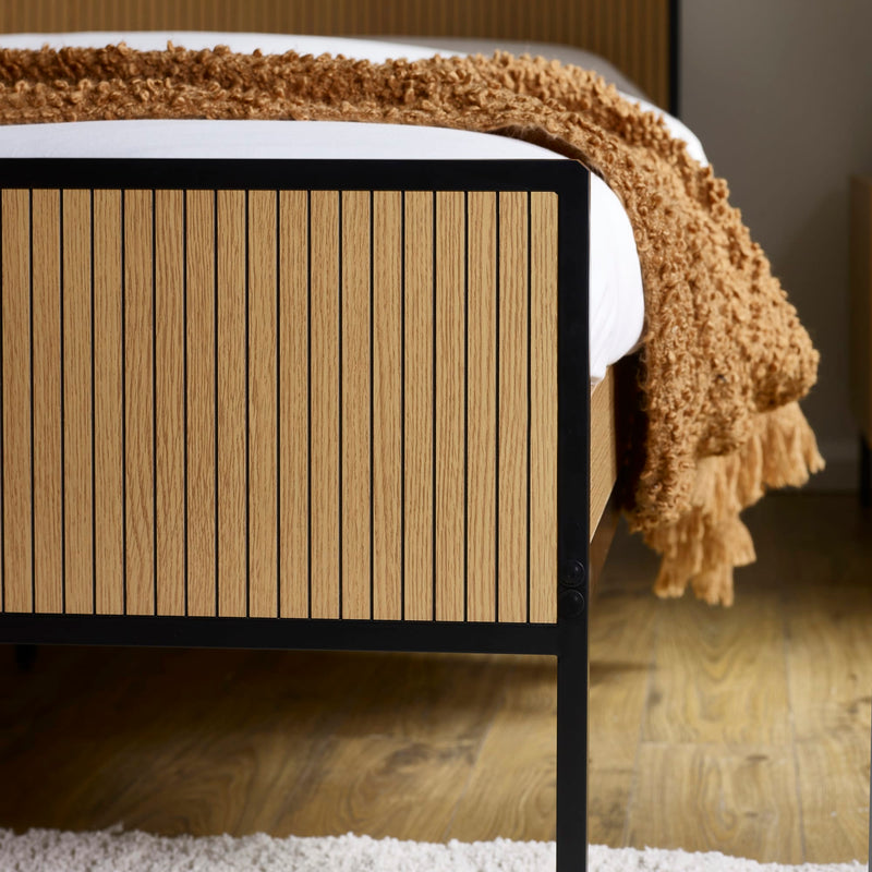 Wooden bed frame with a textured brown blanket in a bedroom setting