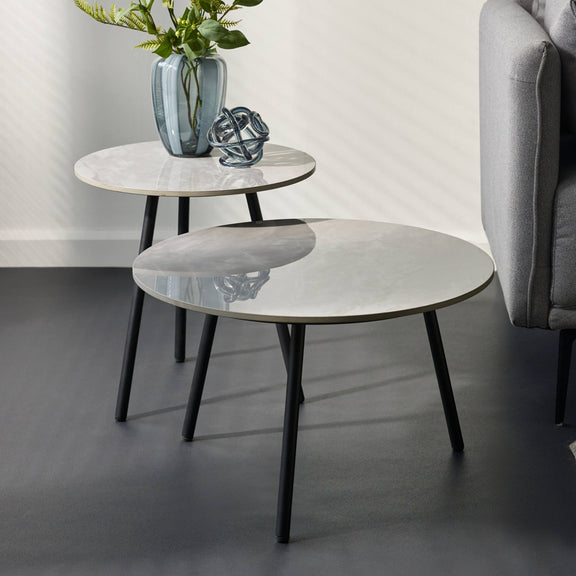 Two marble side tables with black legs in a living room setting.