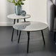 Two marble side tables with black legs in a living room setting.