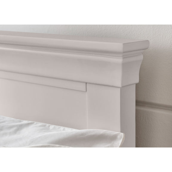 Close-up of a white wooden headboard with a neutral wall background