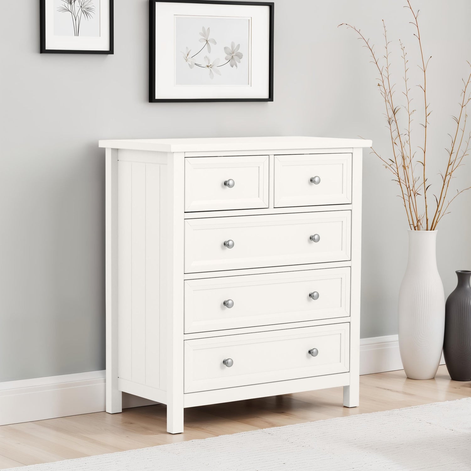 White dresser with four drawers in a room with light gray walls and wooden flooring.