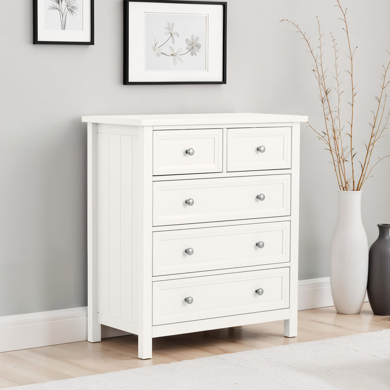 White dresser with four drawers in a room with light gray walls and wooden flooring.