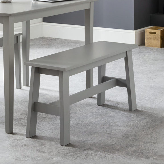Gray bench in a room with a table and a textured floor.