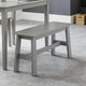 Gray bench in a room with a table and a textured floor.