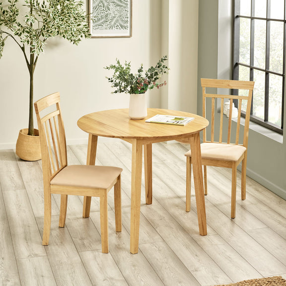 Wooden dining table with four chairs in a room with a window and plant.