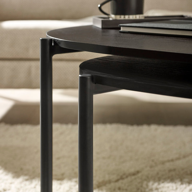 Black coffee table with a cup and books on a beige sofa